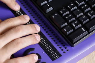Vogelperspektive auf eine Tastatur mit Braillezeile (verweist auf: Barrierefreie Oberflächen entwickeln)
